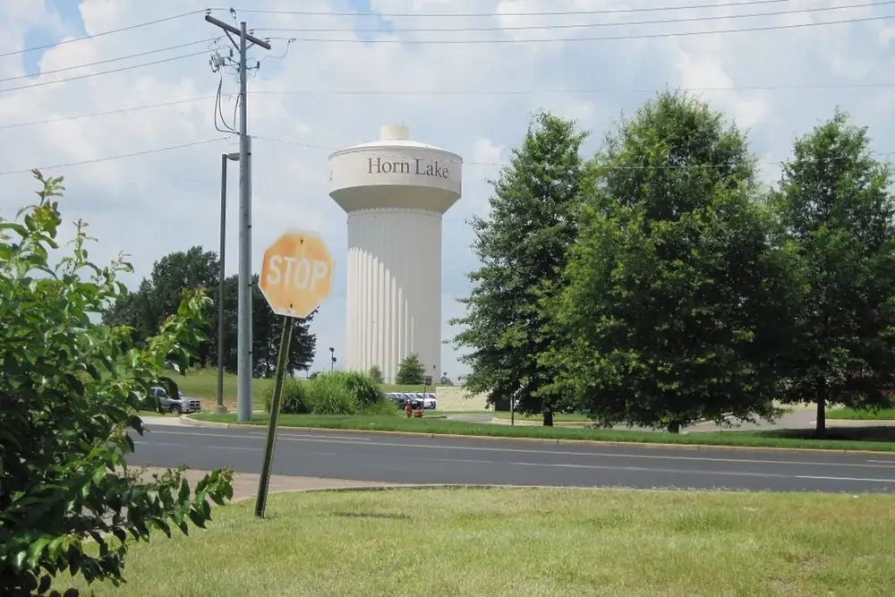 Horn Lake water tower rising above trees and a quiet street in Horn Lake, Mississippi
