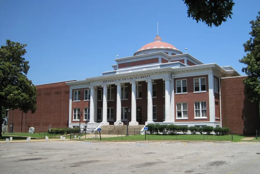 Domed Crittenden County Courthouse with white columns and shade trees in Marion, Arkansas